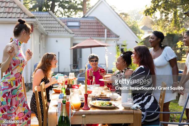 a mixed gathering of women laughing and having fun at a summer garden birthday party celebration lunch - garden brunch stock pictures, royalty-free photos & images