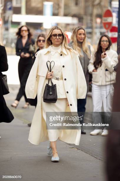 Julia Comil wears a pale yellow coat, the same matching color maxi skirt, top, and a vest, a black Fendi bag, and light pale blue Fendi shoes outside...