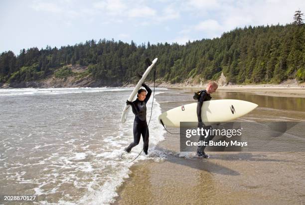 Male and female surfers on the beach at Oswald West State Park on the Oregon Pacific Coast near Lincoln City, Oregon, 2009. .