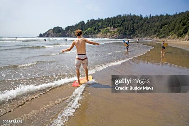 Teenager on a skim board riding in the surf at Oswald West State Park on the Oregon Pacific Coast near Lincoln City, Oregon, 2009. .