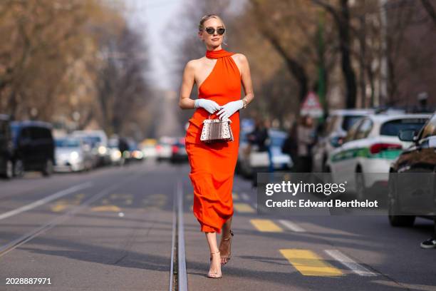 Leonie Hanne wears sunglasses, a red gathered sleeveless dress, a white gloves, a brown and white leather Fendi bag, outside Fendi, during the Milan...