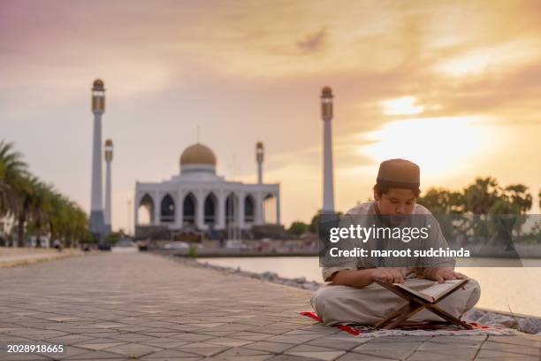 ramadan,asian muslim boy is sitting and reading the quran. the peace in the mosque - book icon stock pictures, royalty-free photos & images