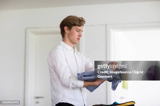 young man packs suitcases at home - fashion man single casual shirt stock pictures, royalty-free photos & images