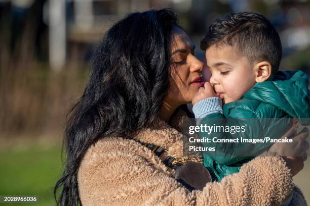 nederland - illustratief beeld  moeder heeft haar peuter op de arm en knuffelt met hem  ze zijn in de wijk op een zonnige winterse dag  dagelijks leven van een moeder met haar jongste kind  foto: anp / hollandse hoogte / patricia rehe - moeder met kind stock pictures, royalty-free photos & images