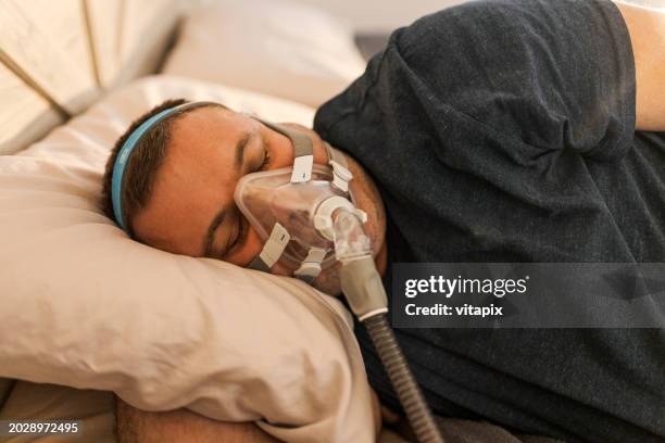 hombre durmiendo con la máquina cpap encendida - obesidad fotografías e imágenes de stock