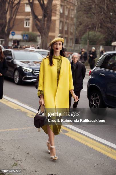 Guest wears a yellow beret hat, a yellow jacket, a khaki green shiny silk dress, a brown leather Dior Saddle bag, pointed golden shiny shoes with...