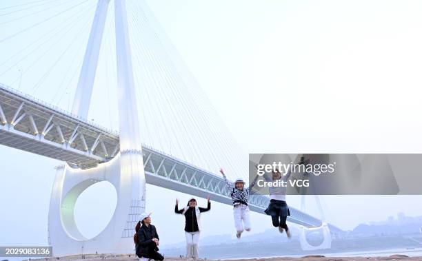 Tourists pose for a photo in front of Chongqing Baijusi Yangtze River Bridge on February 20, 2024 in Chongqing, China. The Baijusi Yangtze River...