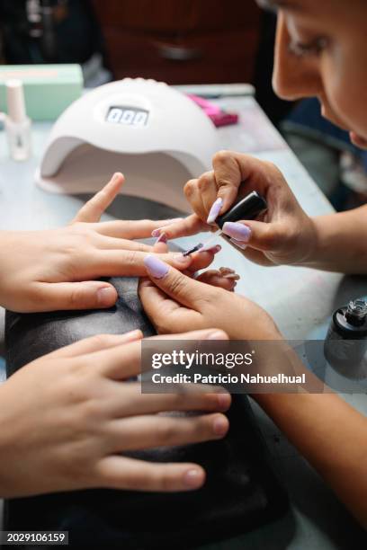 delicate hand detailing: female nail artist demonstrating manicure technique, expertly using painting nails of her client - manicure foto e immagini stock