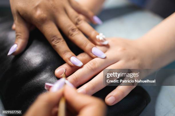 close up of female nail artist doing manicure procedure to woman, using cuticle pusher. - fingernail stock pictures, royalty-free photos & images