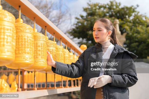 mujer asiática mujer que camina rollo de mano rezando por su deseo giro de mano campanas budistas tibetanas dentro del santuario del monasterio del templo para el espíritu curativo y el espíritu malo limpio en la vida en el templo de la isla de jeju - valle de kathmandu fotografías e imágenes de stock