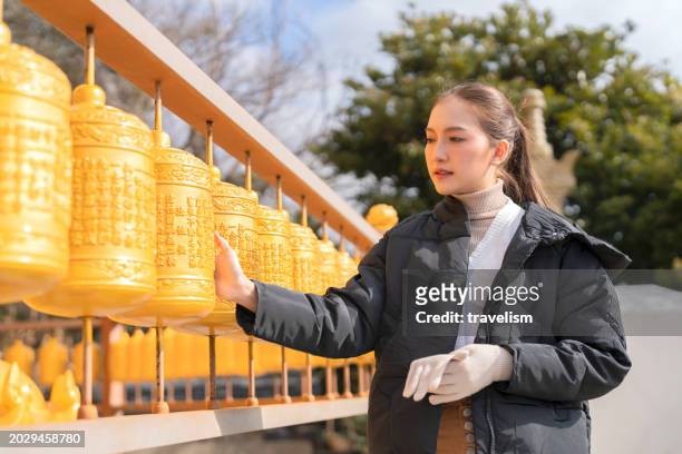 asian female woman walking hand roll praying for her wish hand turn rolltibetan buddhist bells inside temple monastery shrine for healing spirit and clean bad spirit in life in temple at jeju island - kathmandu valley stock pictures, royalty-free photos & images