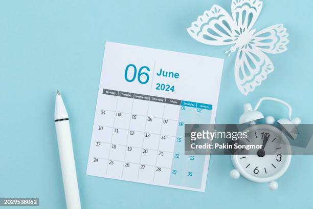 calendar desk 2024: june is the month for the organizer to plan and deadline with white pen and alarm clock against a blue background. - calendar june stock pictures, royalty-free photos & images