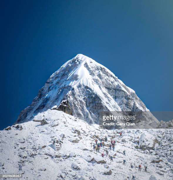 trekkers climb towards pumori on the everest base camp trail - himalayas stock pictures, royalty-free photos & images