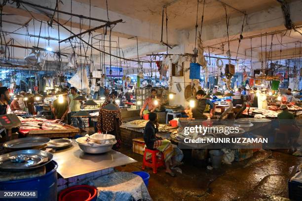 People buy fish at a wholesale market in Dhaka on February 25, 2024.