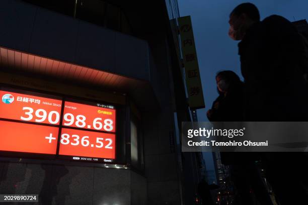 Pedestrians walk past an electronic board displaying the closing figure of the Nikkei Stock Average on February 22, 2024 in Tokyo, Japan. The Nikkei...