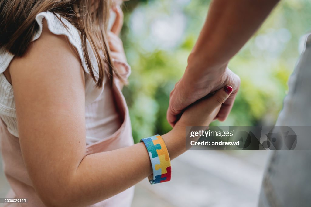 Autistic child holding hands with his mother