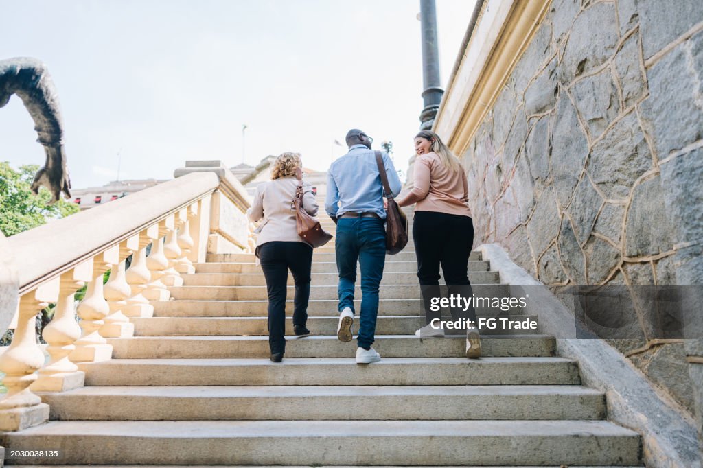 Coworkers talking while moving up the stairs outdoors