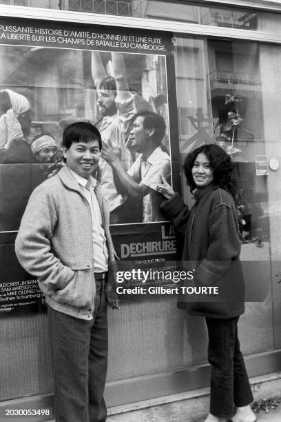 Haing S. Ngor posant devant l'affiche du film 'La Déchirure' à Cannes avec sa nièce réfugiée du Cambodge, le 19 février 1985.