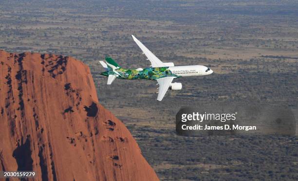An aerial image of an Airbus A220 for QantasLink passing Uluru situated within Uluru-Kata Tjuta National Park on February 22, 2024 in Uluru,...