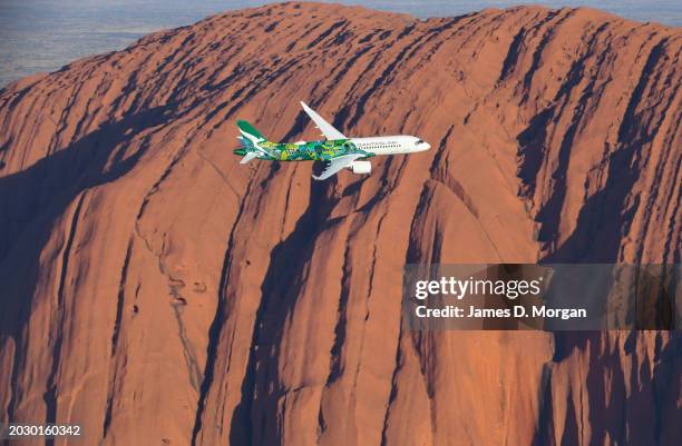 An aerial image of an Airbus A220 for QantasLink passing Uluru situated within Uluru-Kata Tjuta National Park on February 22, 2024 in Uluru,...