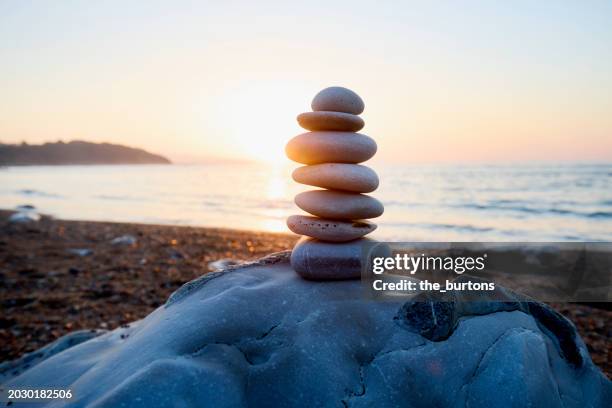 stack of balanced stones at beach against idyllic sunset - stack of sun lounges stock pictures, royalty-free photos & images