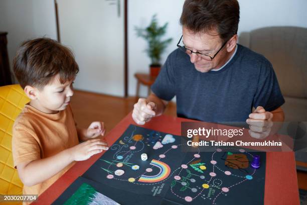 father and son play a board game while sitting at a table in the living room. - 點數 得分單位 個照片及圖片檔