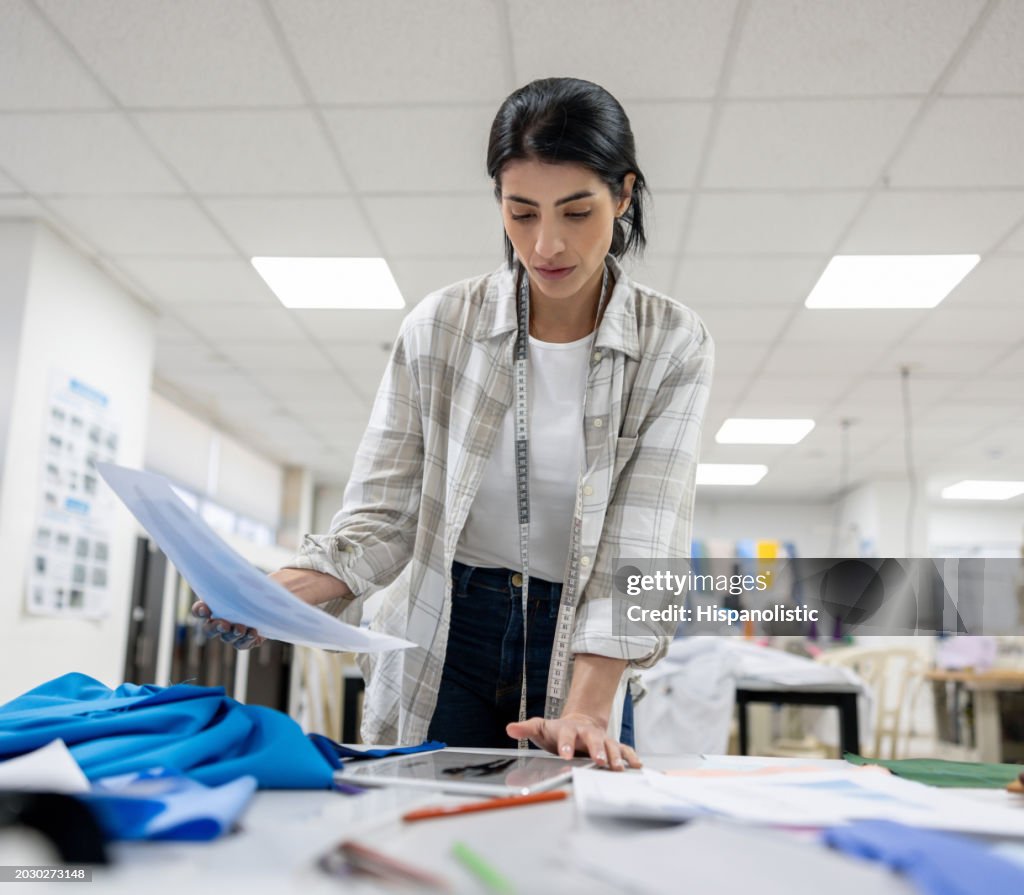 Modedesignerin schaut sich Skizzen an und arbeitet in ihrem Atelier