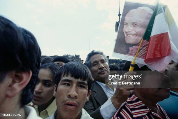 Man holding up a Mexican flag and a photo of Pope John Paul II during a papal visit to Mexico City, January 26th 1979.