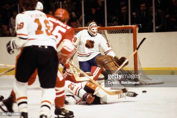 The USSR's Alexander Golikov hits the deck in his bid to score a goal as the NHL All-Stars' goalie Ken Dryden kicks the puck from goal during a...