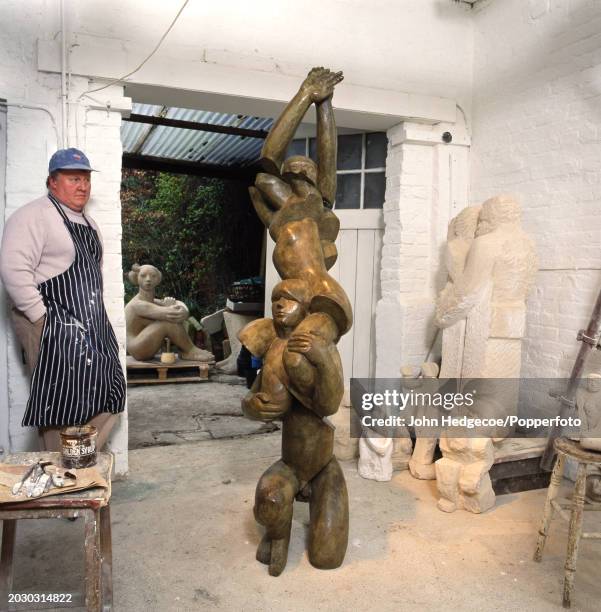 English sculptor Glynn Williams stands with a selection of works in progress in wood and stone in his studio workplace in England in 1992. Professor...