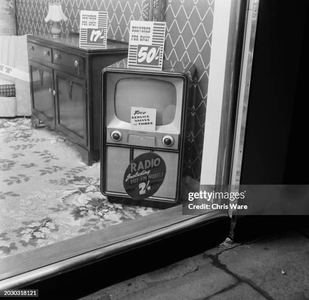 Television set on display in the window of a furniture store in Scunthorpe, Lincolnshire, March 1956. Signs on the cabinet read 'Delivered to your...