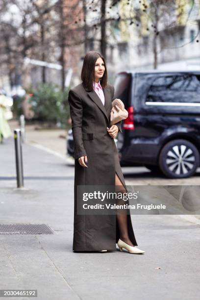 Guest is seen wearing a pink shirt, a beige teddy bag, a brown extra long coat, white cream leather pumps and black tights outside Max Mara show...