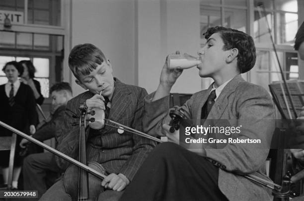 Two boys drink milk in between rehearsals with the London County Council's Symphony Orchestra for Schoolchildren, during a five day holiday programme...