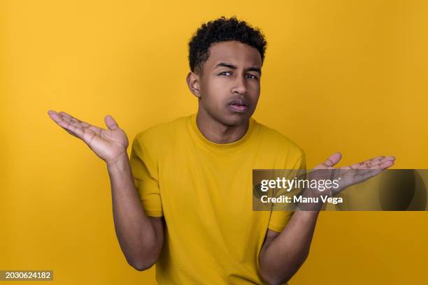 doubtful african american man gestures with his hands in studio shot. - gesticular imagens e fotografias de stock