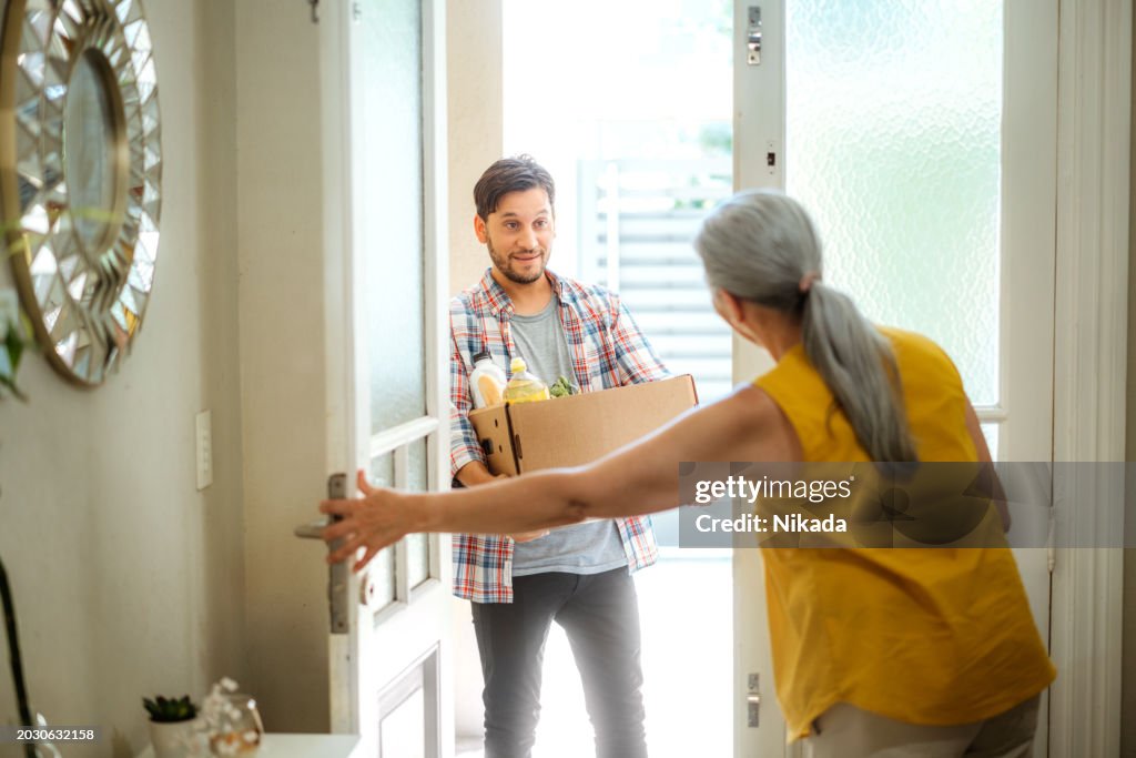 自宅で高齢の女性に食料品を配達する若い男性