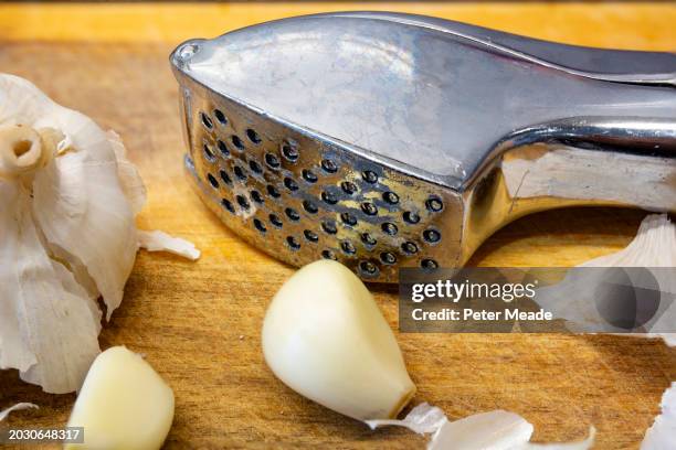 close up of a steel garlic press and fresh garlic - chopping garlic stock pictures, royalty-free photos & images