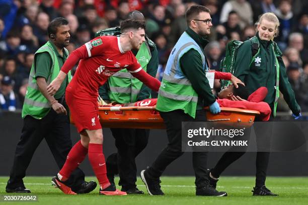 Consoles Liverpool's Dutch midfielder Ryan Gravenberch as he is carried off injured on a stretcher Liverpool's Scottish defender Andrew Robertson...