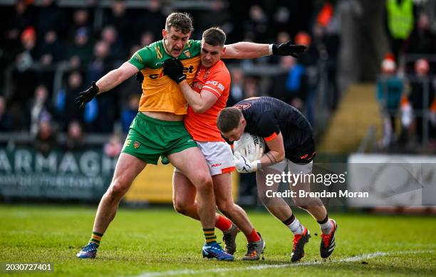 Armagh , United Kingdom - 25 February 2024; Armagh goalkeeper Blaine Hughes gathers possession as Hugh McFadden of Donegal and Greg McCabe of Armagh...