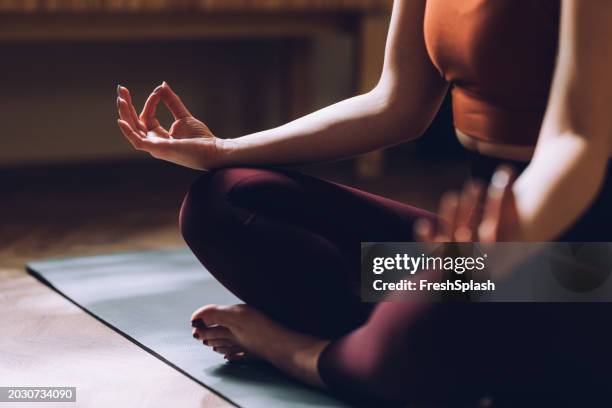 woman practicing yoga meditation on mat in peaceful environment - yoga imagens e fotografias de stock