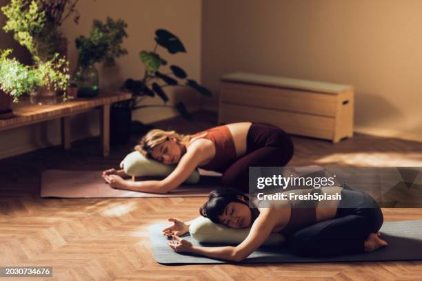 two women practicing yoga poses together in serene home setting - sleep hygiene stock pictures, royalty-free photos & images