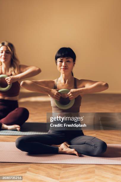 donne impegnate in lezioni di yoga che praticano posture di equilibrio delle braccia - cerchio in metallo da pilates foto e immagini stock