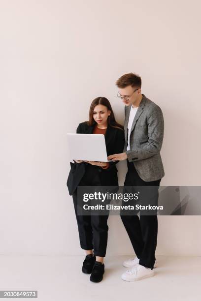 two people in business clothes are looking at a laptop and standing on a white isolated background. place for the text - student desk on white stock pictures, royalty-free photos & images