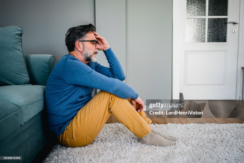 Depressiver Mann, der allein auf dem Boden sitzt