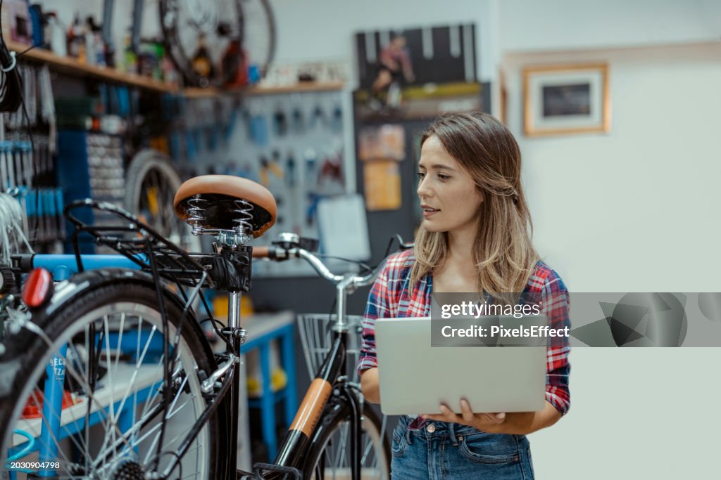Female Bicycle Shop Mechanic Using Laptop