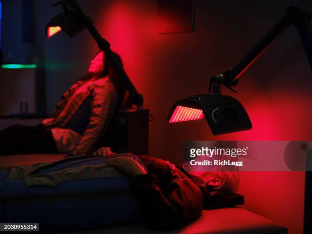 women on an led bed receiving red light therapy and lymphatic detox massage - compression garment stock pictures, royalty-free photos & images
