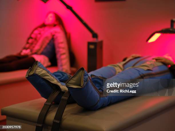 women on an led bed receiving red light therapy and lymphatic detox massage - compression garment stock pictures, royalty-free photos & images