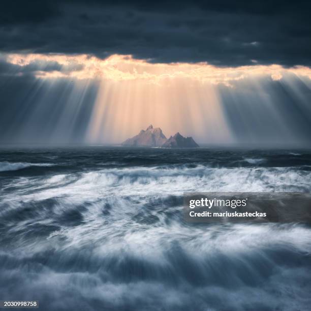 sunlight streaming through dark grey storm clouds, skellig michael (great skellig), county kerry, ireland - atlantic ocean stock pictures, royalty-free photos & images