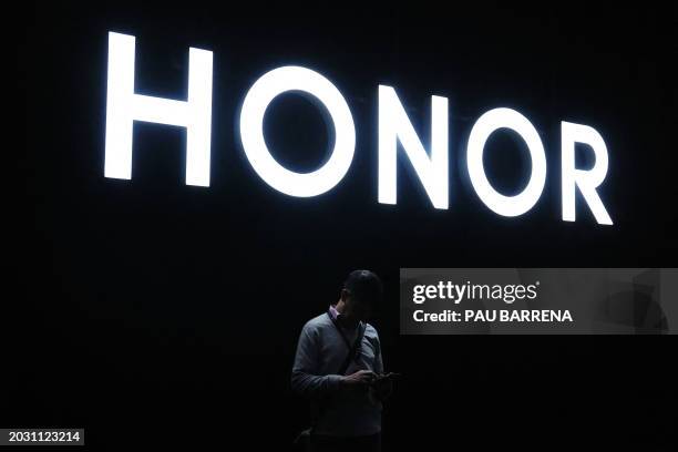 Man uses a smartphones next to the logo of Chinese consumer electronics brand Honor during a presentation at the Mobile World Congress , the telecom...