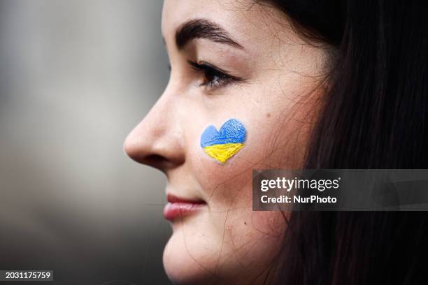 Young woman attends the march ' Together For Victory ' to show solidarity with Ukraine and commemorate two year anniversary of Russian invasion on...