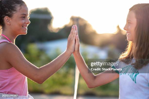 two girls greet each other after playing tennis - tennis ball hand stock pictures, royalty-free photos & images